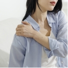 어깨 통증으로 어깨를 감싸 안고 있는 여성